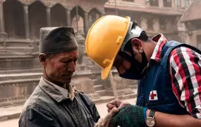 A Red Cross worker tends to an injured Nepali man after an earthquake on Saturday