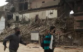 Men run past a collapsed building in Basantapur in central Kathmandu during an aftershock on 25 April 2015. Nepal was struck by a 7.8 earthquake that destroyed historic buildings and crucial infrastructure. 