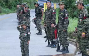 A child in full combat fatigues salutes passers by as rebel fighters from the Moro Islamic Liberation Front (MILF) stand guard by a roadside in southern Mindanao island, Philippines.  