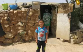 A Palestinian child stands in front of his home in the village of Susiya, in the West Bank. The village is due to be destroyed in the coming weeks