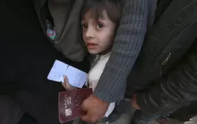 A boy carries identification papers while waiting in line to receive humanitarian aid in Douma, northeast of Damascus, 2014.