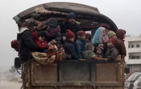 Internally displaced Syrians from western Aleppo countryside, ride on the back of a truck with belongings in Hazano near Idlib.