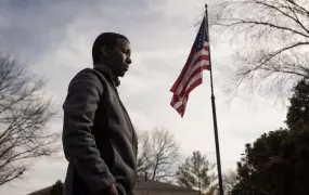 Hussein Mumin walks in front of a raised American flag.