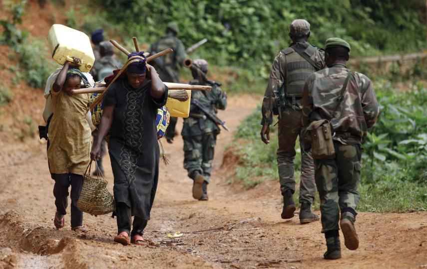 Congolese soldiers patrol against the Allied Democratic Forces rebel group in North Kivu province, in 2013. Also pictured, two women carrying supplies on their backs.