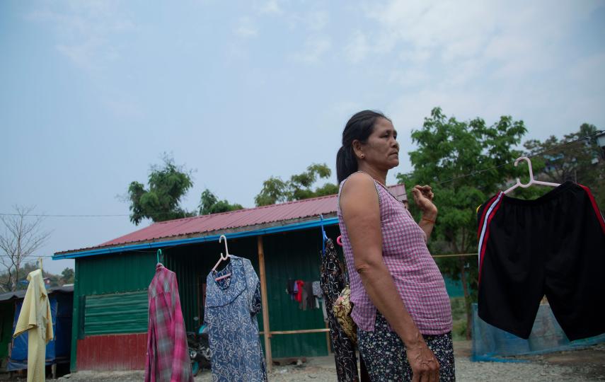 This photo shows Ma Thet standing on the right side of the image next to a clothing line.