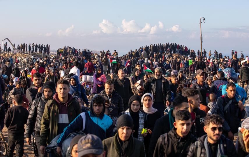 Pictured are Palestinians returning to northern Gaza after Israel began allowing them to cross the Netzarim corridor on 27 January. People can be seen carrying items and Palestinian flags. 