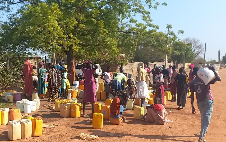 Residents of Abyei town gather at a water point and take shade under a tree. The arrival of displaced people from Sudan has strained local infrastructure in the disputed region. 