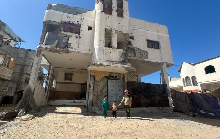Three of Mohamed al-Astal's children in front of their partially destroyed home in Khan Younis, Gaza.