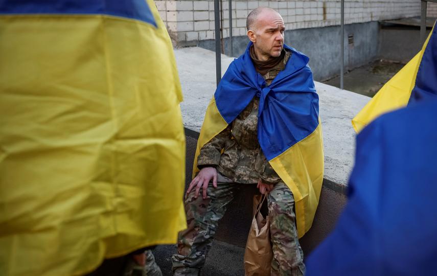 A Ukrainian prisoners of war (POW) returns after a swap. He wears the Ukrainian flag over his shoulders.
