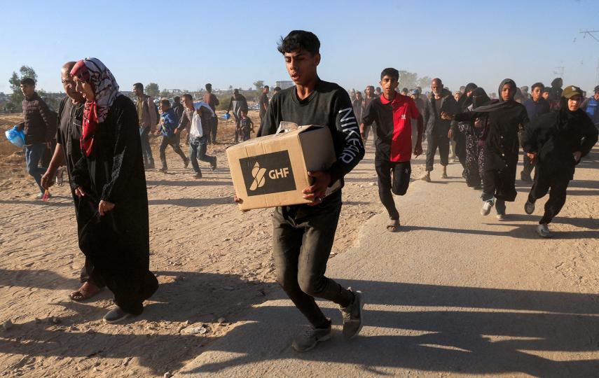 A young man carries aid supplies from the Gaza Humanitarian Foundation in the chaos surrounding the first distributions from the US- and Israeli-backed organisation.