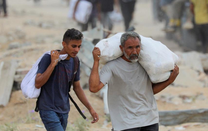 Palestinians carry aid supplies which they received from the U.S.-backed Gaza Humanitarian Foundation (GHF), in the central Gaza Strip, August 1, 2025.