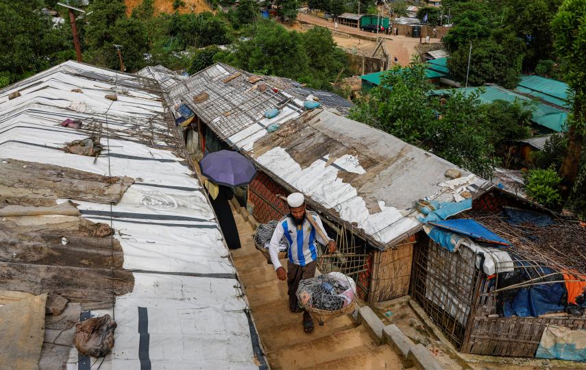 A man carrying goods on his shoulder walks through a Rohingya refugee camp in Cox’s Bazar, Bangladesh, on 17 August 2025.
