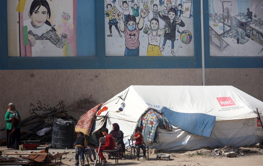 Displaced Palestinians stand in front of their tents next to the offices of the UN's agency for Palestine refugees (UNRWA) in Gaza City.