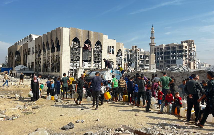 Children collect water from a delivery truck provided through a local initiative. They are living in a makeshift camp inside the Islamic University of Gaza.