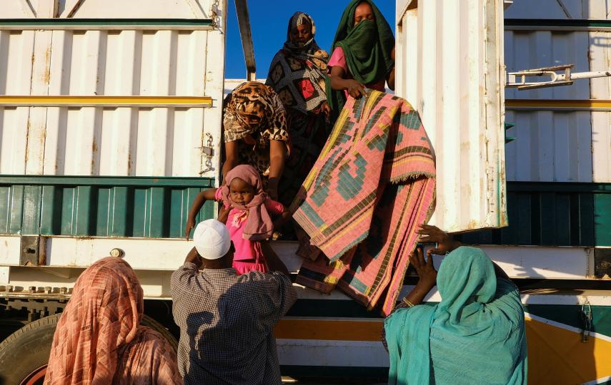 People displaced by RSF atrocities in El Fasher climb down from a truck that took them to a camp in the town of Al-Dabba, on 19 November 2025.