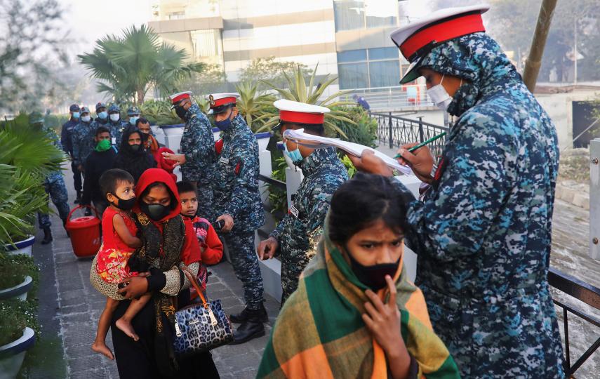 Bangladesh navy personnel check a group of Rohingya refugees before they board a ship for Bhasan Char island, on 29 December 2020.
