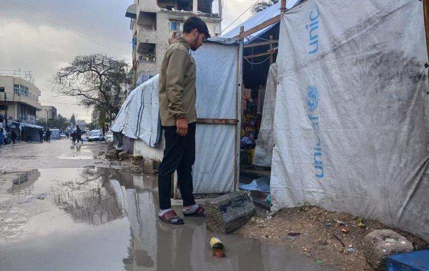  A Palestinian man stands in a puddle left by a recent storm outside of a tent in Gaza City.