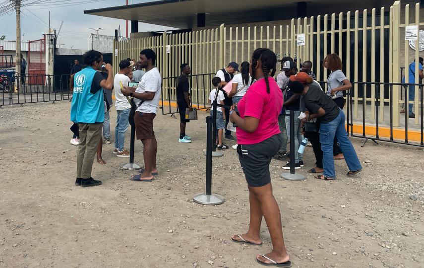 A staff member from the UN refugee agency UNHCR speaks with people applying for asylum in Tapachula outside the COMAR centre in the city.