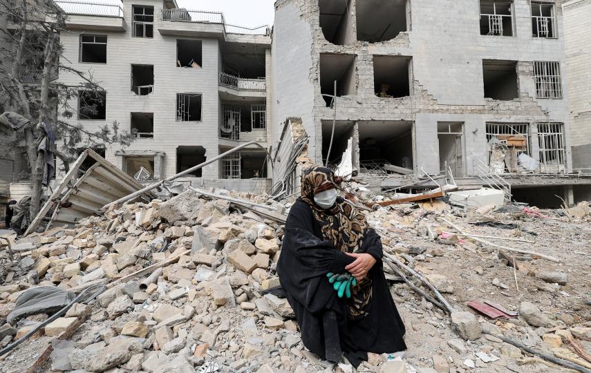 Amid daily US-Israeli bombardments, a woman sits outside what was her Tehran apartment after it was destroyed by an airstrike while she was inside, on 12 March 2026.