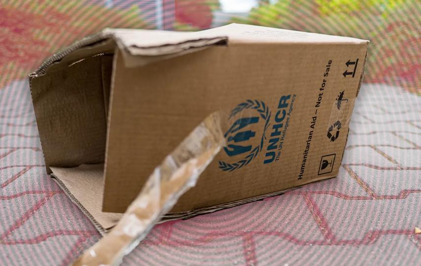An empty UNHCR Humanitarian Aid box lies discarded outside a metro station.