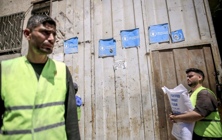 People carry aid packages as Palestinians gather to receive a distribution of flour and food parcels by the World Food Programme in Gaza City on 3 June 2026.