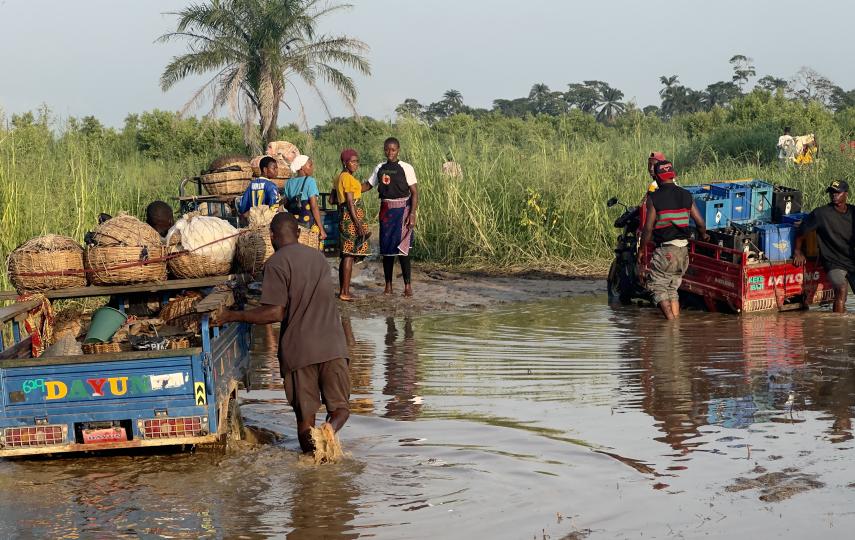 Unale residents pictured pushing cargo through muddy road puddles in June 2026.