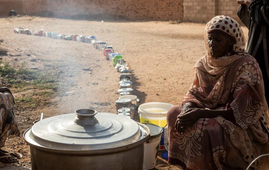 A Sudanese woman from a community kitchen prepares meals for people who are affected by conflict and extreme hunger and are out of reach of international aid efforts, as empty pots are seen lined up to receive food, in Omdurman, Sudan on 19 September 2024