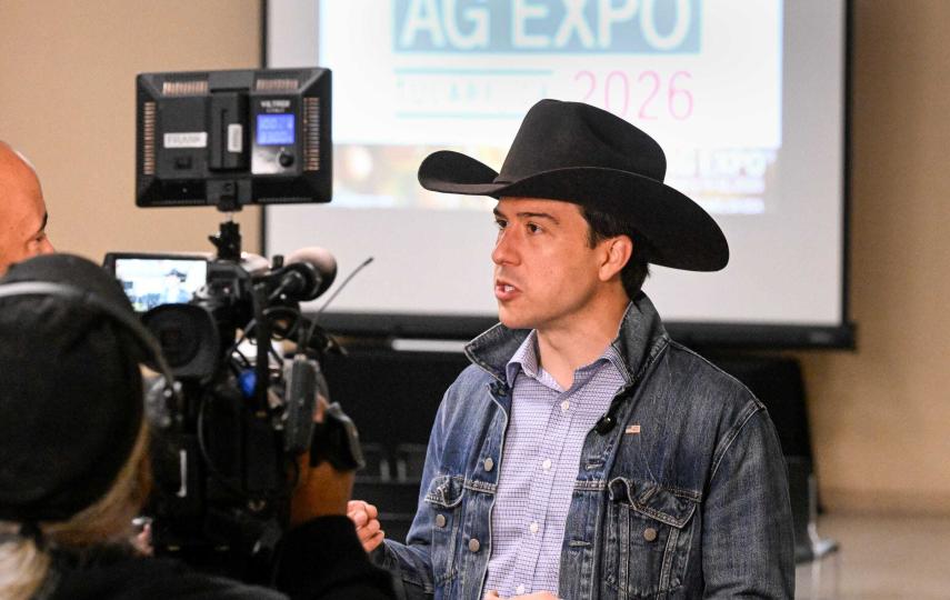 A man in a cowboy had in front of a camera at a conference.