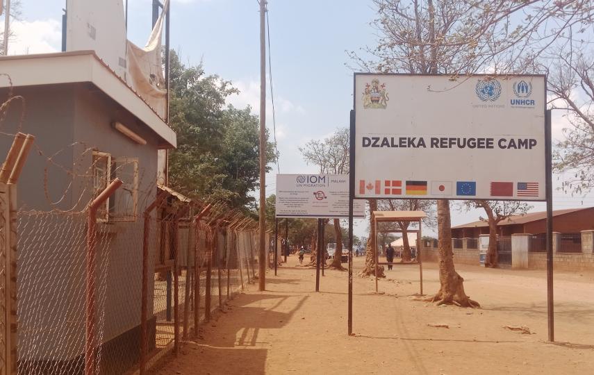 A photo showing a sign that reads "Dzaleka Refugee Camp"