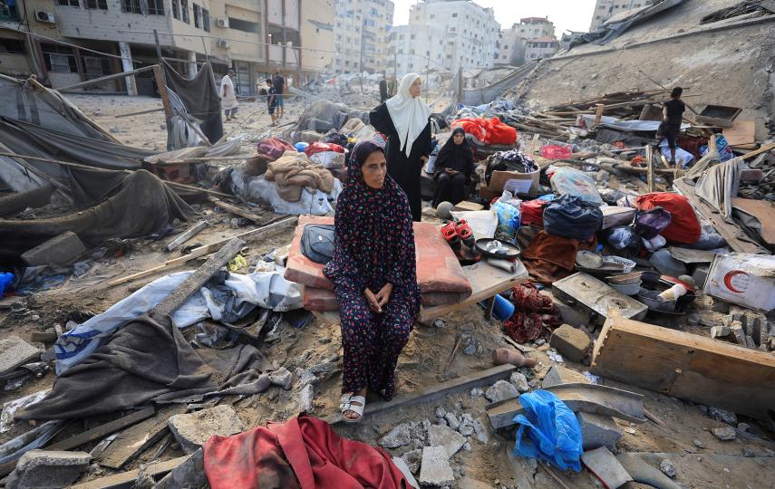 A Palestinian woman sits amidst debris as people inspect the site of an Israeli strike on a house whose residents were pre-warned by the Israeli military to evacuate, in Gaza City, 30 July 2026.