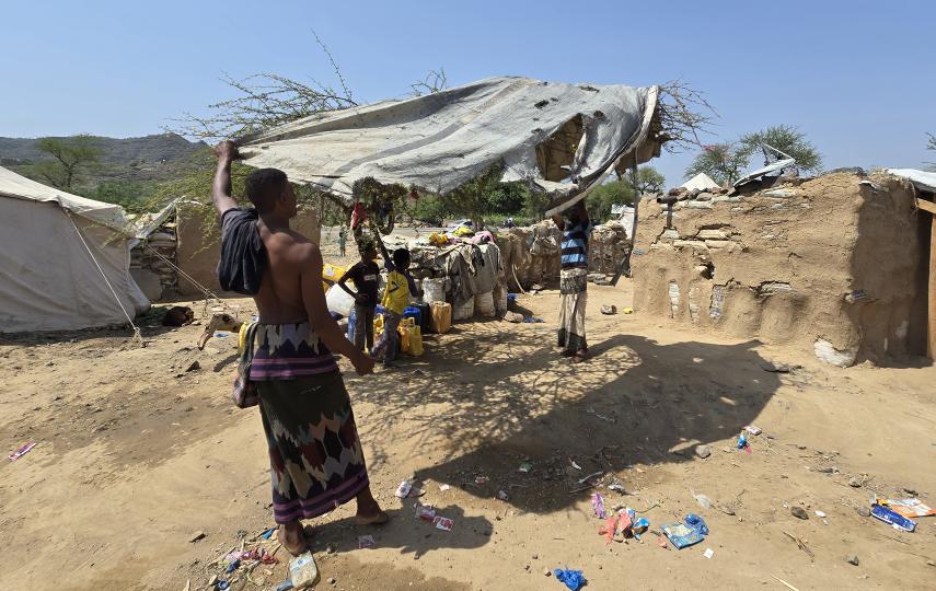 Two people spread a tarp at a camp in Taiz.
