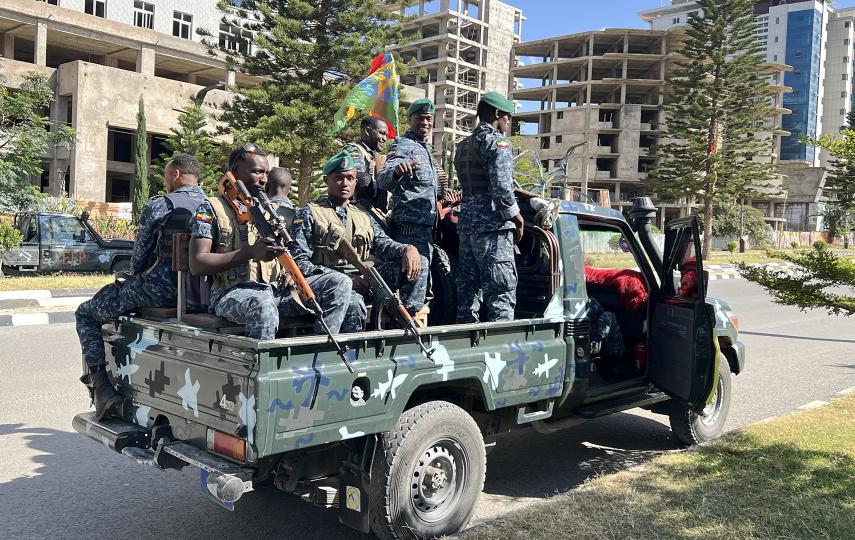 Troops in the back of a truck drive through a city