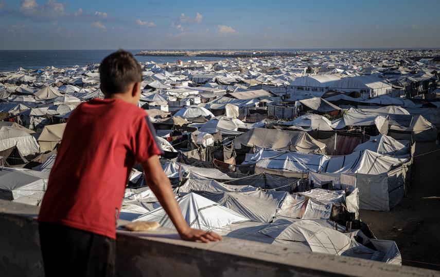 A Palestinian boy overlooks a vast displacement camp by the sea in Gaza City.