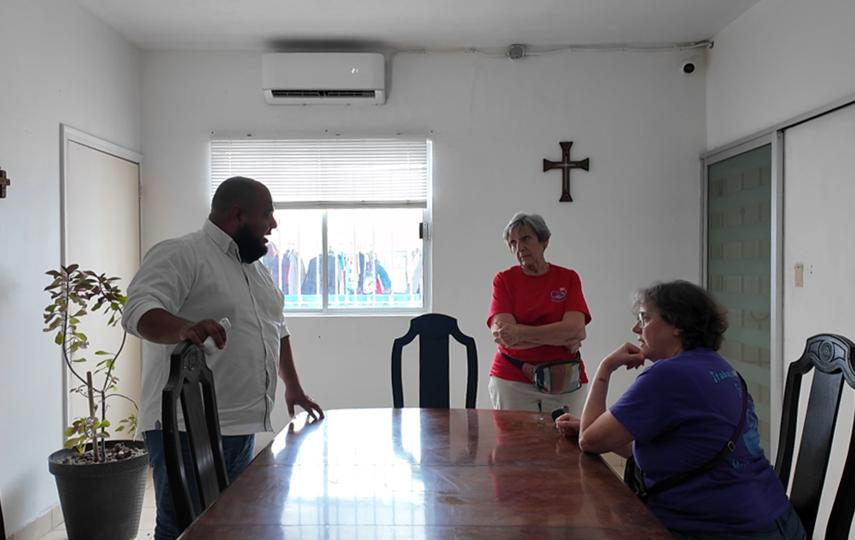   Casa del Migrante director José Luis Elías Rodríguez and long-time humanitarian volunteers in southern Texas, Kathy Harrington and Andrea Rudnik are pictured at a table discussing.