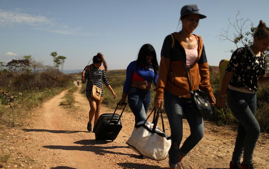 Venezuelan migrants walk along a trail