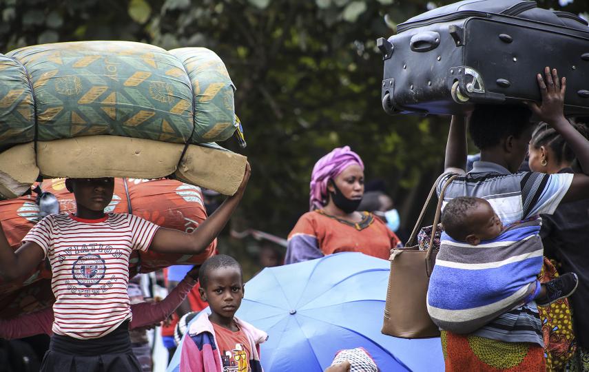 A group of people carry their belongings on the move.