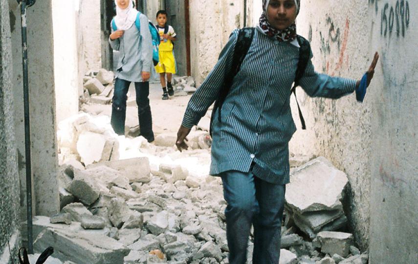 A Palestinian girl attending a UNRWA school side-steps the rubble of a damaged home