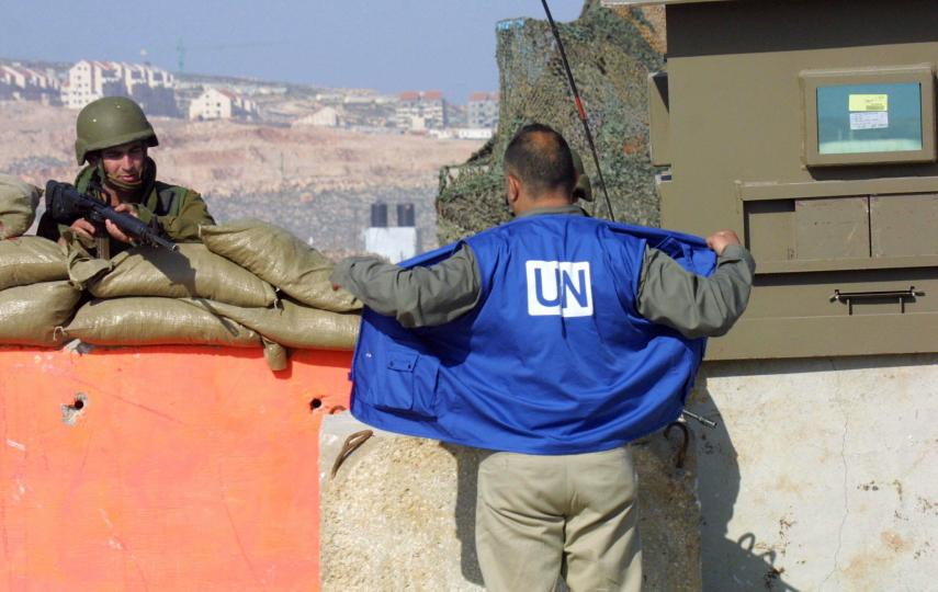 A UN staff member being checked by Israeli soldiers at a checkpoint.