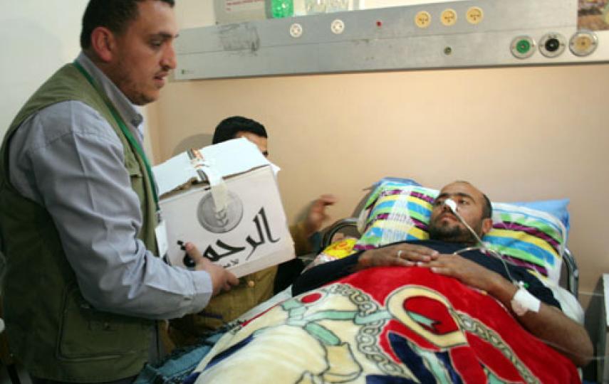 An aid worker from Al-Rahma brings provisions to a patient in a Gaza hospital during an Israeli military offensive in the Strip