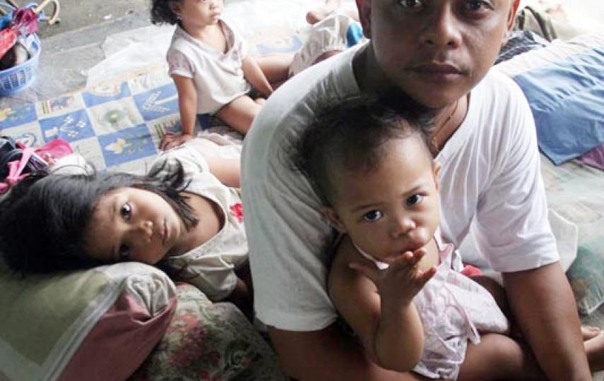 Cainta, Philippines - Ryan Leyva, 25, ponders the future with his children at an evacuation camp in the Philippines. Levya says life at the crowded evacuation centre has been hard, but he was lucky to survive Manila's epic flooding
