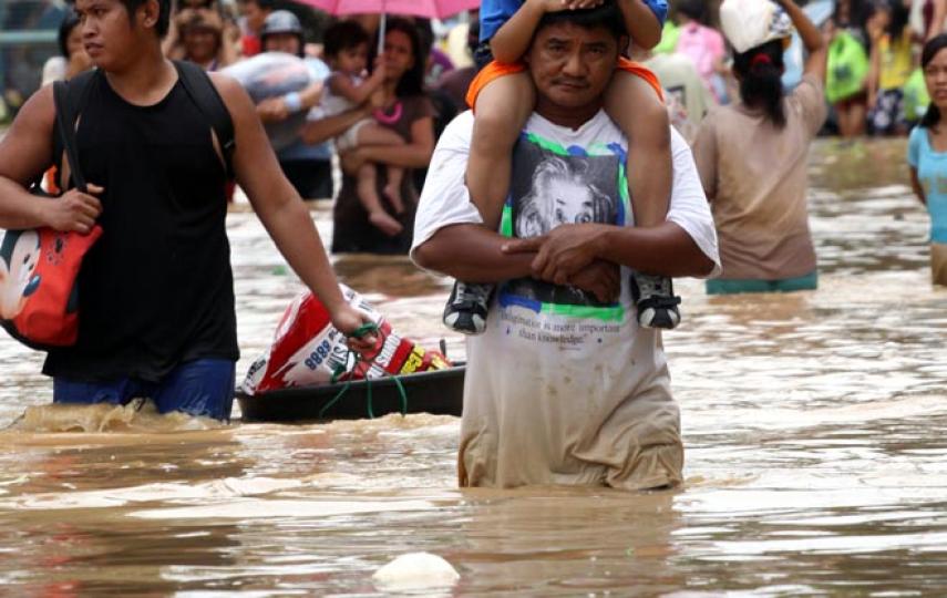 Manila - A father carries his daughter on his back as they wade through putrid, brown flood water in suburban Pasig district in Manila. At least 246 people were killed by tropical storm Ketsana on 26 September