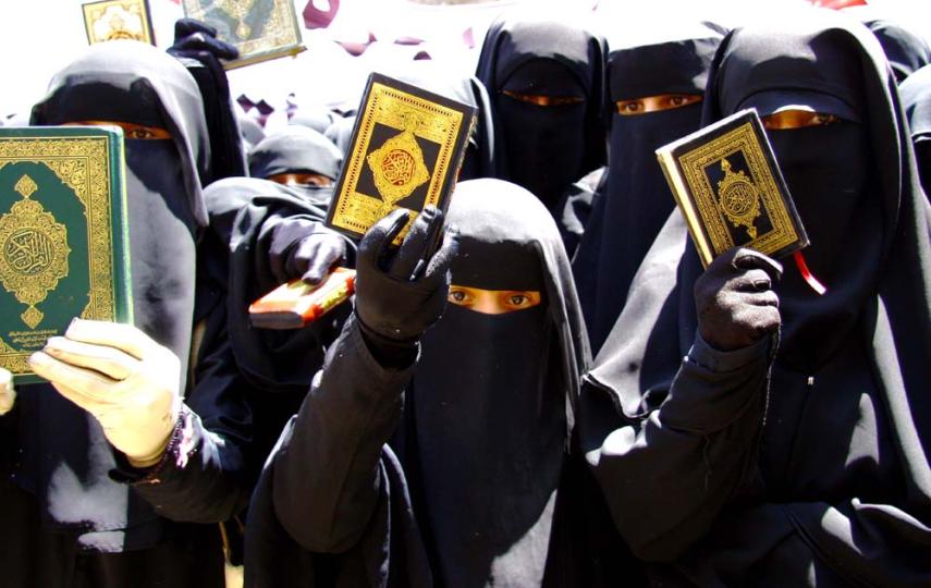 Women protesters hold up copies of the Quran outside parliament in Sanaa while stating that a proposed law banning marriages under the age of 17 in Yemen is un-Islamic