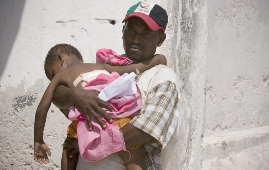 A man holds his child who has been wounded by an explosion in recent fighting, at an Outreach Therapeutic Centre Programmes (OTPs) on the edge of the African Union (AU) peacekeeping military base on April 3, 2010 in Mogadishu