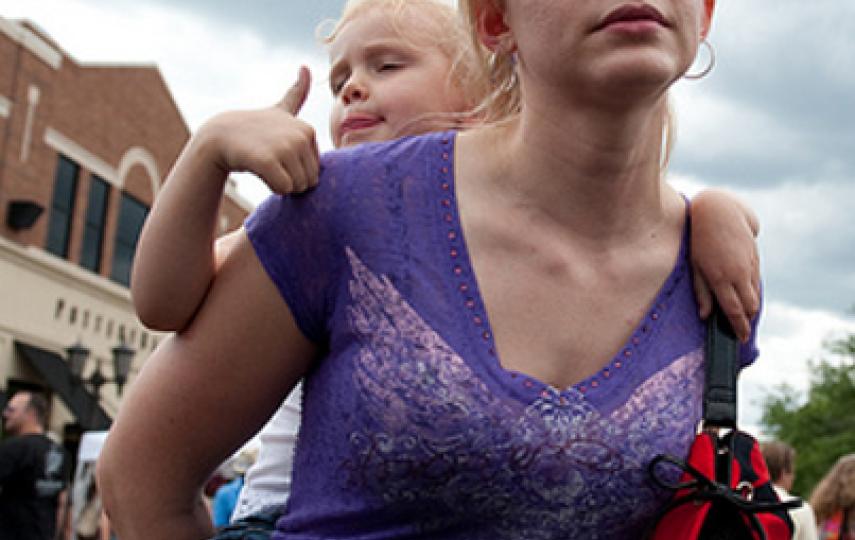 A mother carries her daughter across Victoria St. during Grand Old Day in St. Paul