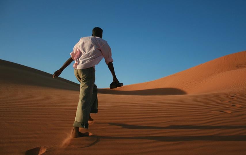 Man walking across a sand dune in Northern Sudan. For generic use