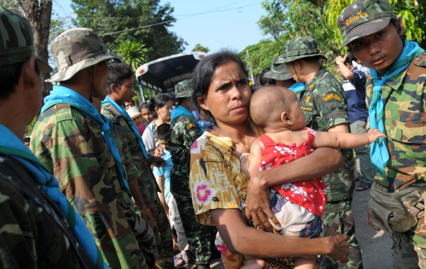 A refugee from Myanmar walks past Thai security officials, 9 November at Base 369 of the Thai Border Patrol Police in Mae Sot district, which was used to shelter some 15,000 refugees