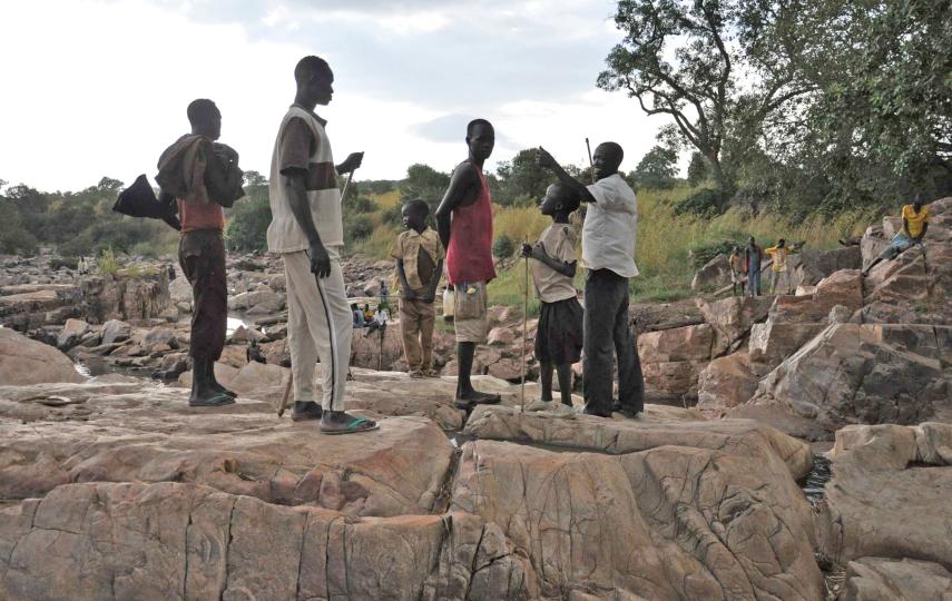 Men at a river near Sali, trying to catch fish for their families camped nearby in the woods after fleeing Antonov bombs. The women look for gold in the river during the day to try and sell at Kurmuk market to buy food after abandoning their farms