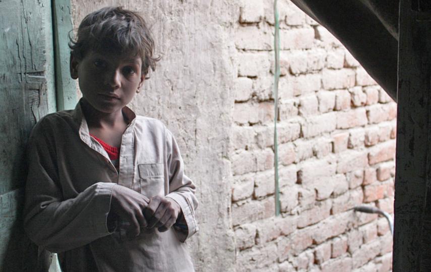 A young Afghan boy stands outside his two-room mud and brick house in an informal settlement of eastern Afghanistan. His family has struggled to re-integrate since returning in 2006 from Pakistan, where they were refugees. This boy was born in Pakistan