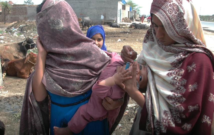 A polio worker on the outskirts of Peshawar in Pakistan delivers vaccine drops, but many workers are now too scared to go into the field.