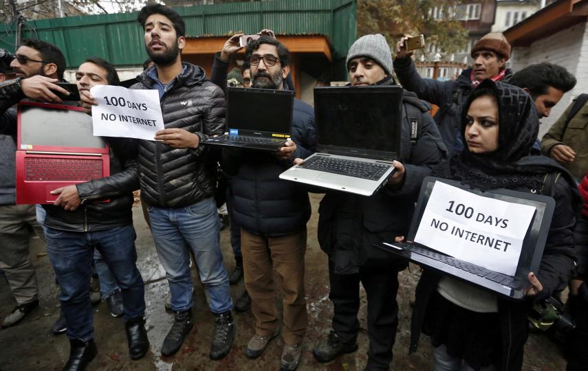 Kashmiri journalists display laptops and placards during a protest